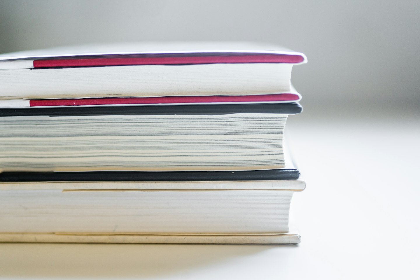 Una pila ordenada de libros o cuadernos en un estante.